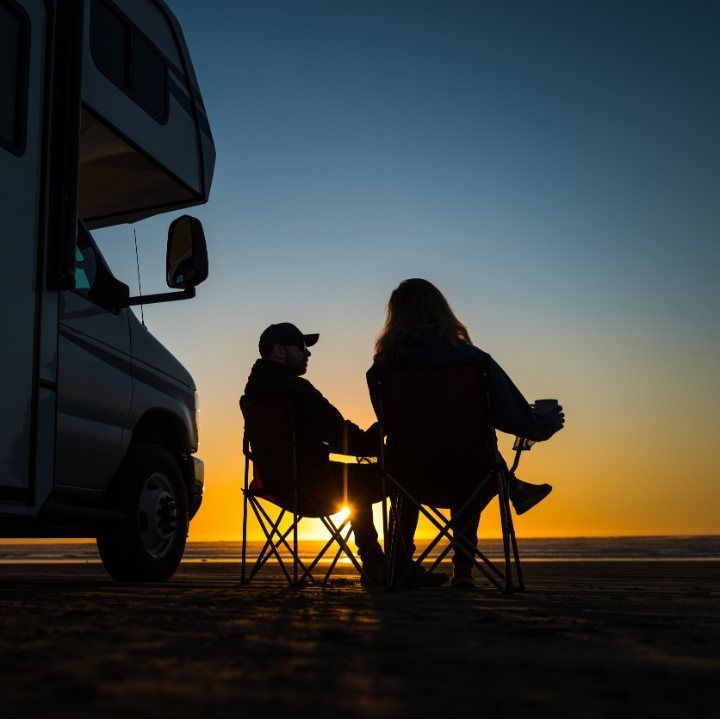 imagen nocturna de dos personas sentadas al lado de una camper